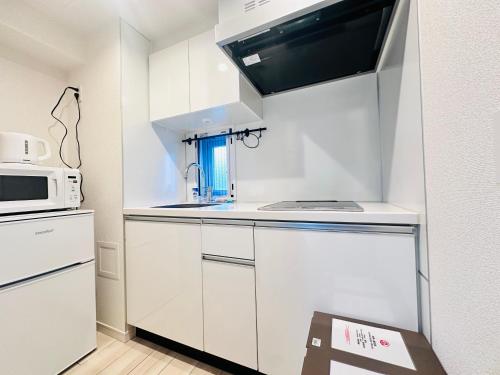 a kitchen with white cabinets and a microwave at REGNO COMFORT ASAKUSA Ⅳ in Tokyo