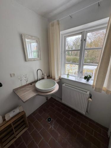 a bathroom with a sink and two windows at Skelby Præstegård lej 1 in Gedser