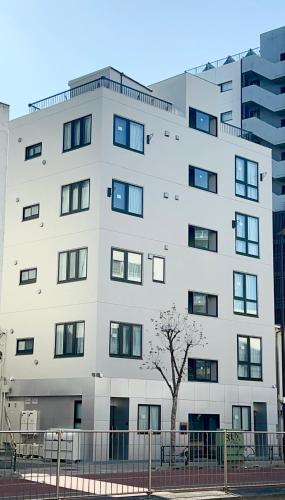 a large white building with a tree in front of it at AKATSUKI HOTEL Ueno JR山手線鶯谷駅まで徒歩3分 成田空港直行 新宿渋谷直通 in Tokyo