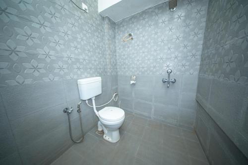a bathroom with a white toilet and a shower at Aqua Wave by YogiTree Hotels in North goa