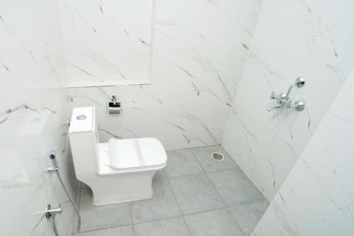 a white bathroom with a toilet and a sink at Hotel The Black Diamond in Bangalore