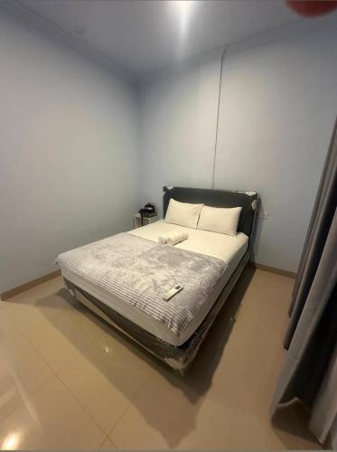 a bed in a room with a white wall at Cherry Homestay in Kuta Lombok