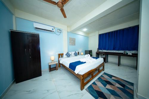 a bedroom with a bed with blue walls and a piano at Aqua Wave by YogiTree Hotels in North goa