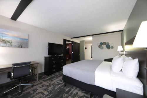 a hotel room with a bed and a desk and a television at Quality Inn & Suites Mattoon South in Mattoon