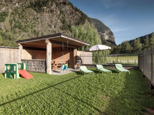 a gazebo with chairs and an umbrella in a yard at MYALPS Mühlhof inklusive Sauna in Oetz
