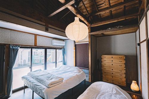a bedroom with two beds and a large window at 松本市の静謐と温もりあふれる隠れ家邸宅 in Matsumoto
