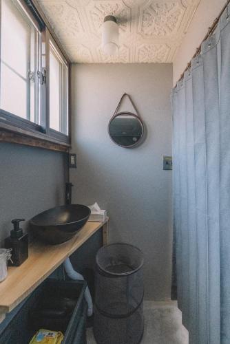 a bathroom with a sink and a mirror and a window at 松本市の静謐と温もりあふれる隠れ家邸宅 in Matsumoto
