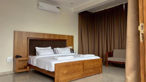 a bedroom with a large bed with a wooden headboard at Hill View Resort - Kannur in Pālayangadi