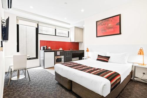 a bedroom with a large bed and a kitchen at Comfort Apartments Box Hill in Box Hill