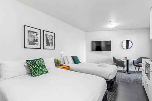 a hotel room with two beds and a desk with a tv at Quality Apartments North Melbourne in Melbourne