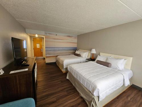 a hotel room with two beds and a flat screen tv at Clarion Pointe South Portland in South Portland