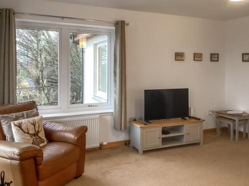 a living room with a couch and a television at Shedfield Cottage in Drumnadrochit