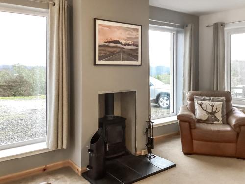 a living room with a fireplace and a chair at Shedfield Cottage in Drumnadrochit