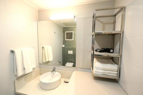 a white bathroom with a sink and a mirror at Sirius Town by AntalyaSuites in Antalya