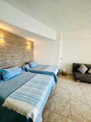 a hotel room with two beds and a couch at Suite Acapulco vista al mar in Acapulco