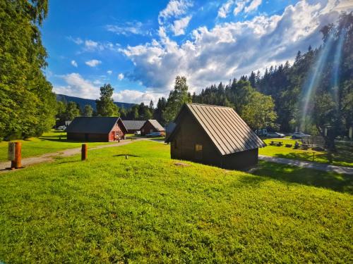 a barn on a green field with a rainbow in the sky at Chalets & Apartments - Base Camp Medvědín in Špindlerův Mlýn