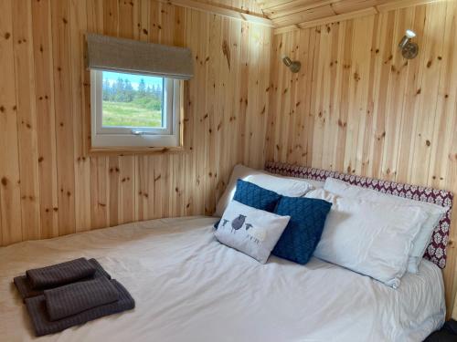 a bed in a wooden room with a window at Shepherd's hut 2 at Braebost Croft in Portree
