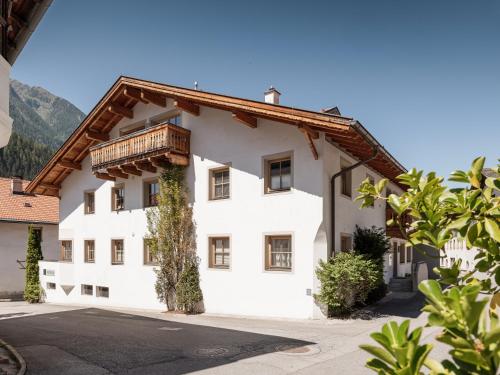 a white building with a wooden balcony on it at MYALPS Historical in Oetz