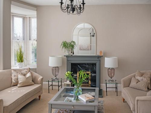 a living room with a fireplace and a chandelier at Lovely Little Let in Birnam
