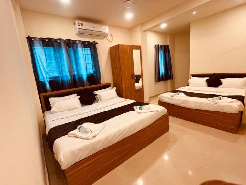 ein Hotelzimmer mit zwei Betten und einem Spiegel in der Unterkunft Siya dormitory and rooms in Kolhapur