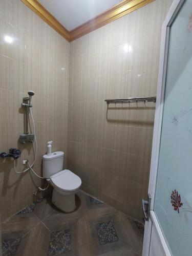 a bathroom with a white toilet in a room at Clara Guest House in Seturan