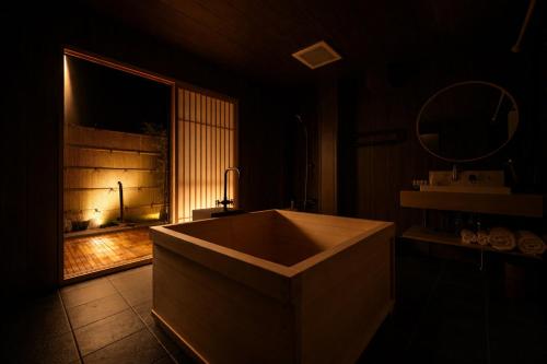 a bathroom with a large tub in a dark room at Ryokan Suzuri 旅館 すずり in Tokyo