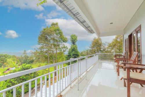 a balcony with chairs and a view of trees at DWM Mandhasativa Homestay By Reccoma in Singaraja