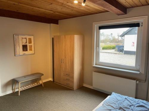 a bedroom with a window and a bed and a cabinet at Marskferie Tønder in Tønder