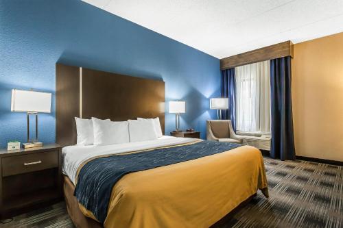 a hotel room with a large bed and a chair at Comfort Inn Cleveland Airport in Middleburg Heights