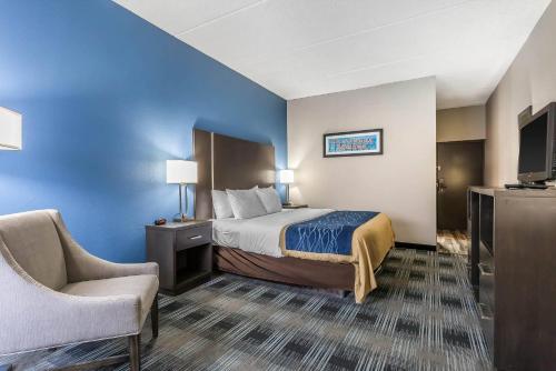 a hotel room with a bed and a chair at Comfort Inn Cleveland Airport in Middleburg Heights
