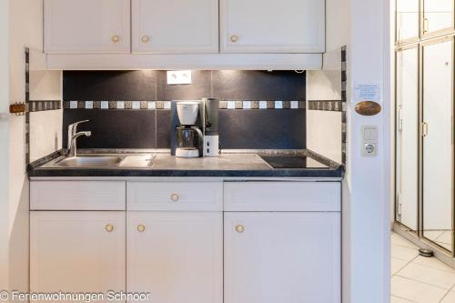 a kitchen with white cabinets and a sink at Ankerplatz 607 in Schilksee