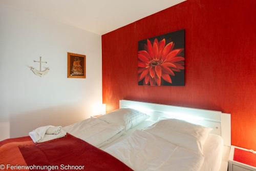 a bed in a room with a red wall at Ankerplatz 607 in Schilksee