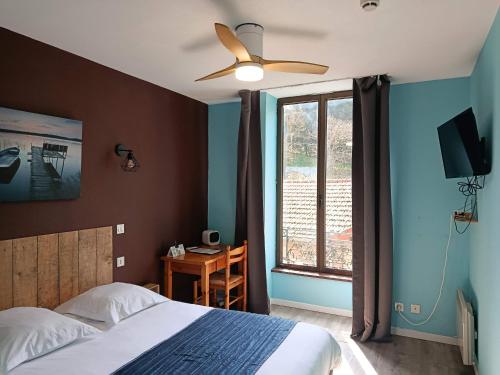 a bedroom with a bed and a ceiling fan and a desk at Logis Hôtel Le Saint Clément in Saint-Clement-sur-Valsonne