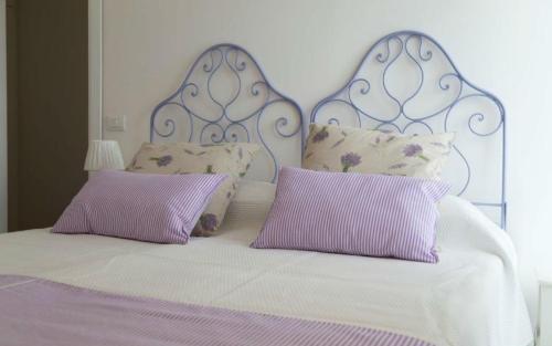 a bed with purple and white sheets and pillows at Frasteva Resort in Valverde