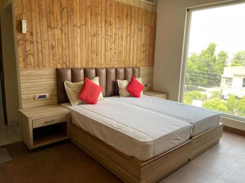 a bedroom with a bed with red pillows and a window at Hotel Tushar Elegant in Ghaziabad