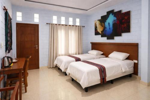 a bedroom with two beds and a table and a desk at Dermaga Resort Pramuka in Pulau Pramuka