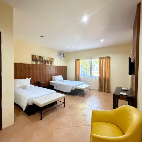 a hotel room with two beds and a yellow chair at Sierra Resort in Dauin