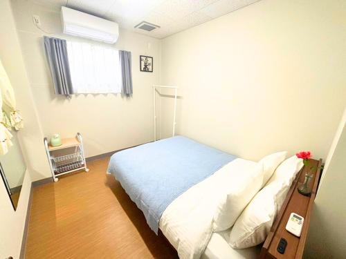 a small bedroom with a bed and a window at Magokoro House 202 in Nishiizu