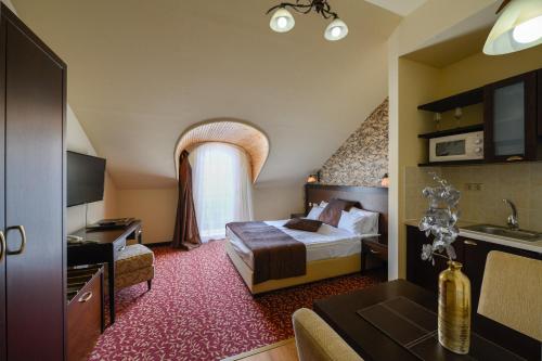 a hotel room with a bed and a kitchen at Hotel Aurum in Hajdúszoboszló