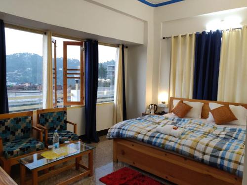 a bedroom with a bed and a couch and windows at Hotel Ratnouday in Kāndi