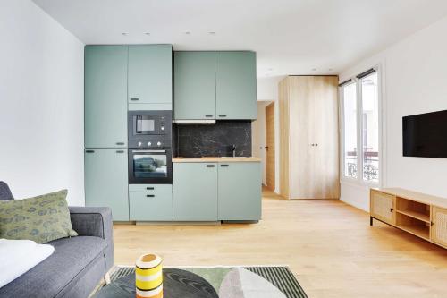 a living room with blue cabinets and a kitchen at Charming studio for 2P - near Parc Monceau in Paris