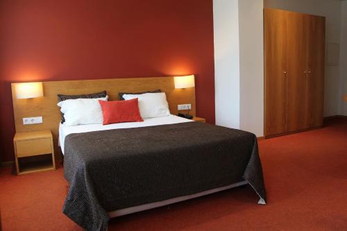 a bedroom with a large bed with a red wall at Paredes Hotel Apartamento in Paredes