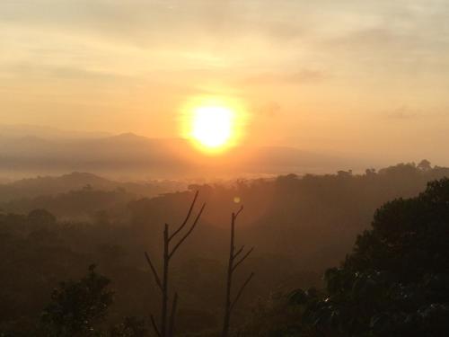 a sunset in the mountains with the sun in the sky at Casa Libertinn in Manuel Antonio