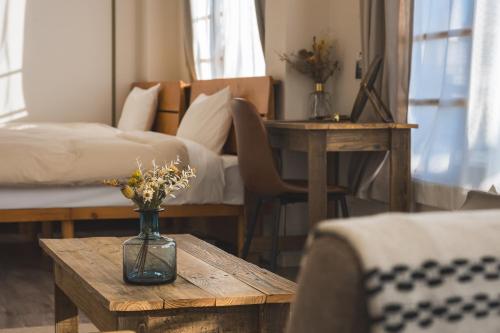 a bedroom with a bed and a vase with flowers on a table at wanderlust STAY in Kofu