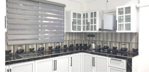 a kitchen with white cabinets and black counter tops at Sevmeth Villa in Kandy