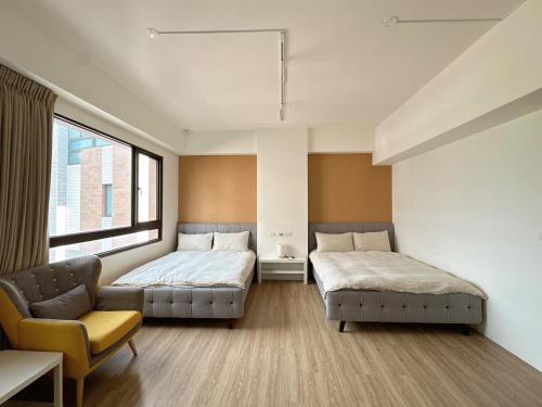 two beds in a room with a couch and a chair at 9 Tan Yuan Homestay in Jiaoxi