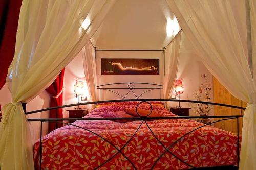 una camera con letto rosso a baldacchino di Mulino Baiar a Stregna