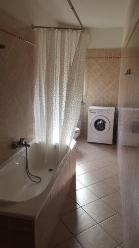a bathroom with a bath tub and a washing machine at Casa Vacanze Capoterra in Capoterra
