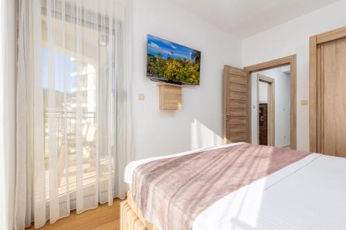 a bedroom with a bed and a television on a wall at Apart hotel KATUNJANIN in Herceg-Novi