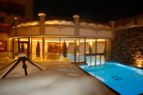a house with a swimming pool in the snow at Savoy Dolomites Luxury & Spa Hotel in Selva di Val Gardena